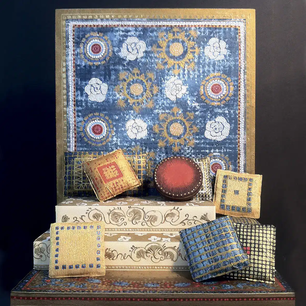 Maquette d'un ensemble de coussins carrés et ronds aux motifs brodés posés sur des marches décoratives. Derrière eux, un grand panneau orné de motifs floraux et géométriques dans des tons bleu, or et rouge. L’atmosphère est riche, artisanale et inspirée des textiles anciens, presque comme un décor de bazar précieux.