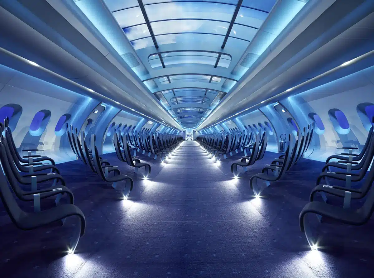 Une cabine futuriste d’avion : rangées de sièges noirs minimalistes, éclairage bleu, et un plafond vitré affichant des images immersives, donnant une ambiance high-tech et irréelle.