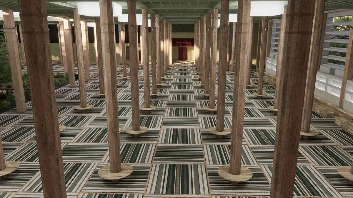 Le défilé Chanel à Dakar, présenté dans l’ancien Palais de Justice, mettait en scène un décor grandiose où l’architecture brutaliste du lieu dialoguait avec des références culturelles sénégalaises. La vaste salle, rythmée par des rangées de piliers monumentaux, formait une perspective sculpturale guidant le regard vers l’entrée solennelle du tribunal. Au sol, un tapis aux motifs graphiques tissés, inspiré des savoir-faire africains, apportait chaleur et texture. La lumière douce et contrôlée révélait la patine du bâtiment, transformant ce lieu institutionnel en un espace poétique, rituel et vibrant, hommage à la création et au dialogue entre Paris et Dakar.