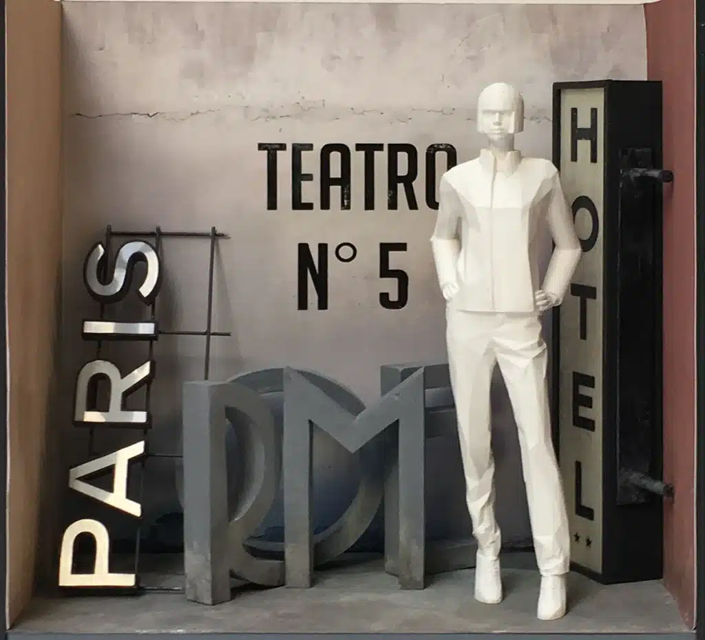 Maquette d'une vitrine inspirée du cinéma italien et de Cinecittà, mêlant grandes lettres sculptées (“PARIS”, “ROME”, “HOTEL”), néons rétro et décor patiné façon studio de tournage. Les mannequins, stylisés en blanc, se détachent dans une ambiance Paris à Rome, entre théâtre, hôtel et plateau de film.