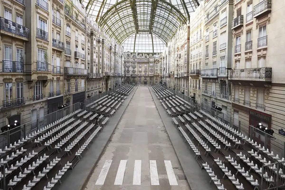 Scénographie du défilé Chanel imaginée sous Karl Lagerfeld, transformant le Grand Palais en rue parisienne grandeur nature. Les façades haussmanniennes, les balcons en trompe-l’œil et la perspective centrale recréent une véritable avenue
