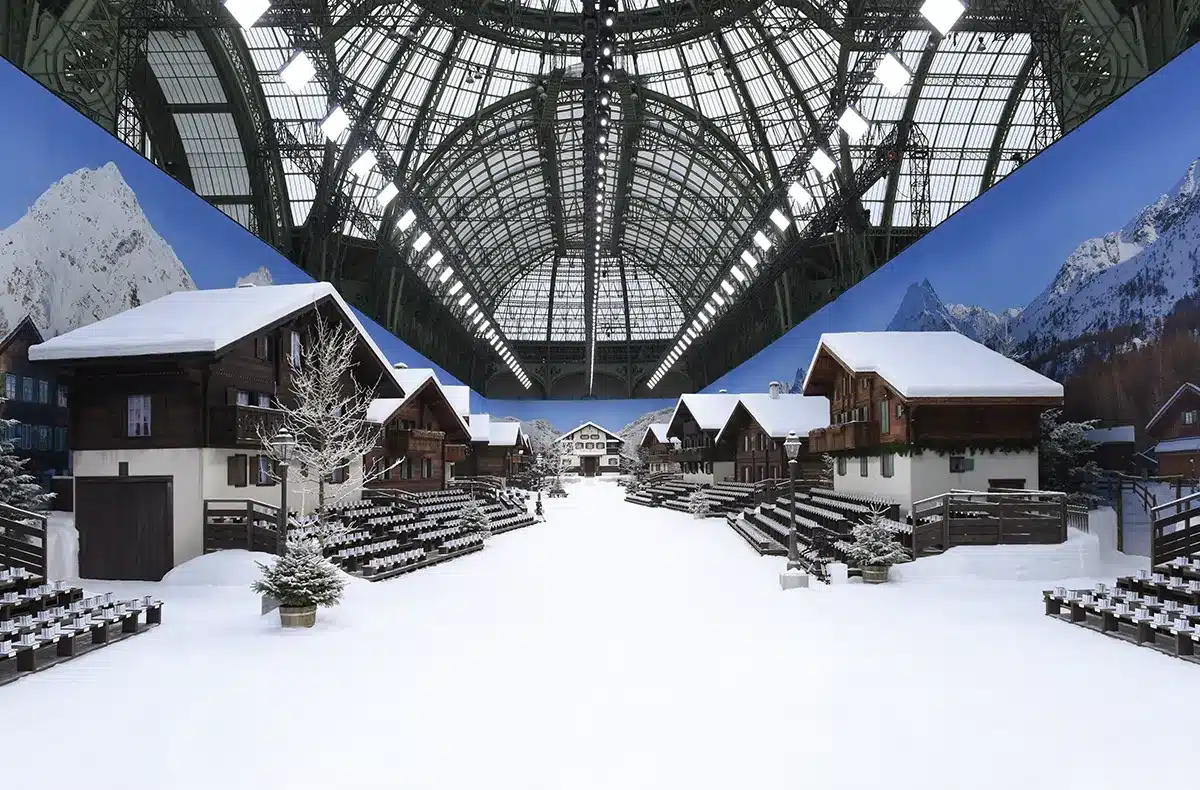 Défilé Chanel au Grand Palais : un décor de village alpin enneigé, avec chalets en bois, allées immaculées et ambiance hivernale recréée sous la majestueuse verrière du Grand Palais.